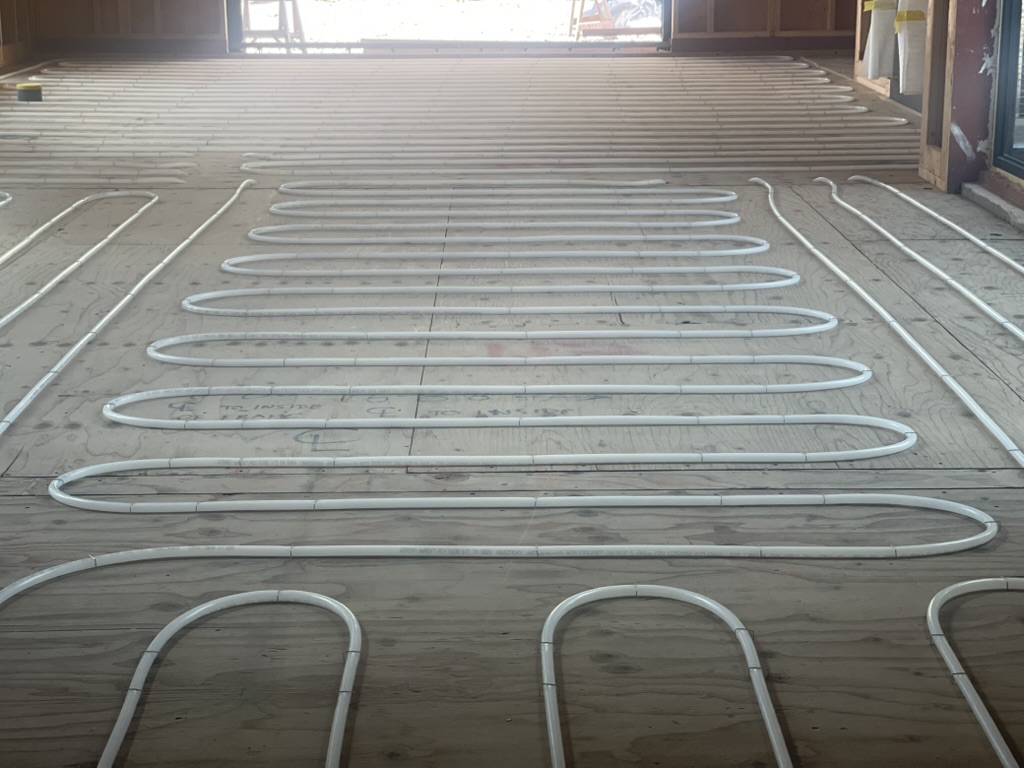 Radiant heating loops stapled across plywood subfloor