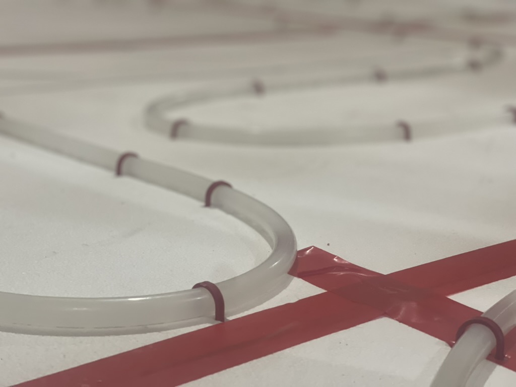 Close-up of PEX tubing clipped over gypsum underlayment