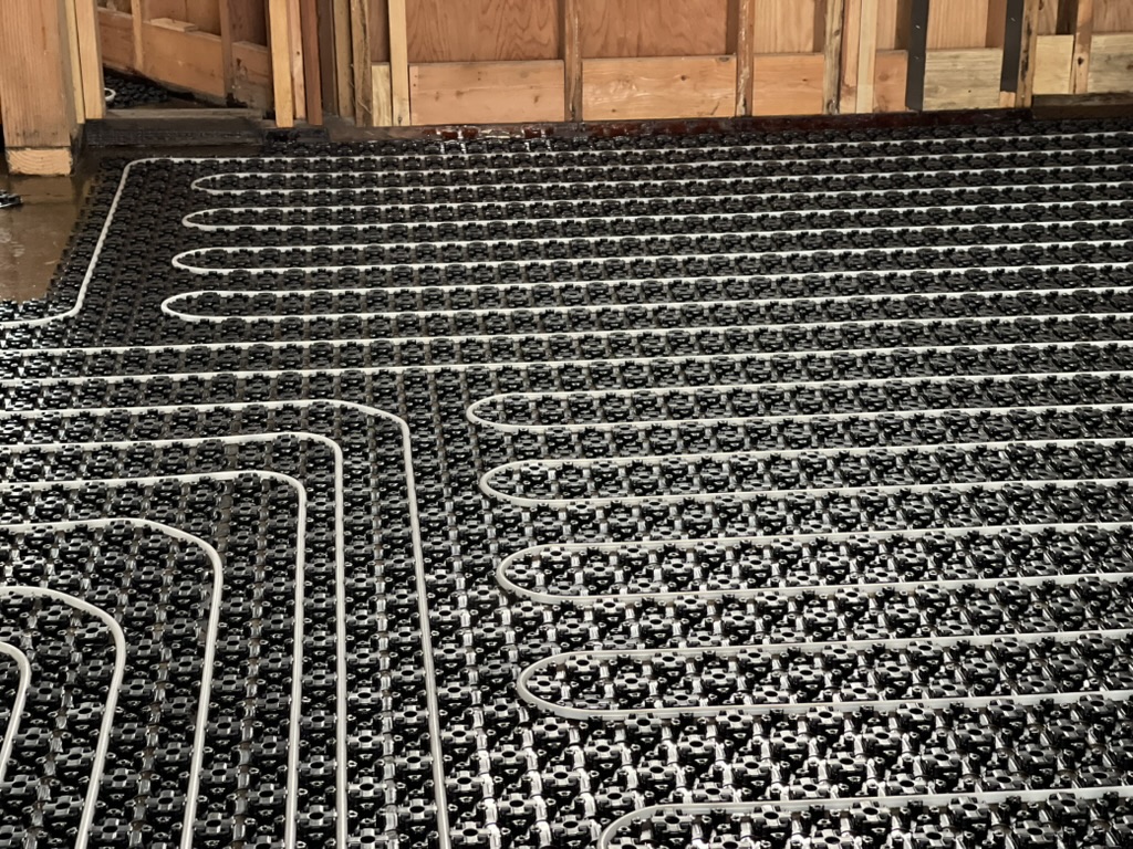 Radiant PEX loops routed through studded floor panels